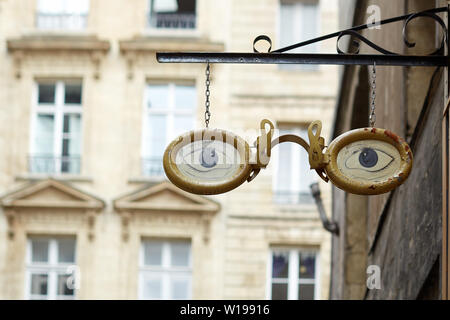 Pair of gold rimmed glasses with blue eyes - creative shop sign design hanging over an opticians shop in a street in Bordeaux Stock Photo