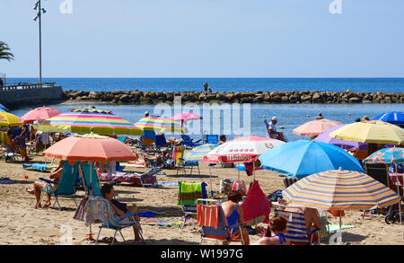 Torrevieja, Spain - June 10, 2019: Lot of people tourists sunbath on popular Playa del cura beach in Torrevieja resort city during sunny warm day, hol Stock Photo