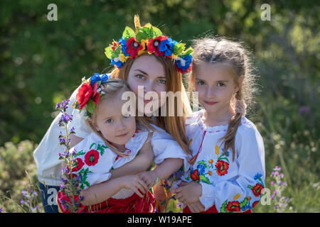 Mother and daughters in traditional Ukrainian costumes posing in the spring countryside Stock Photo