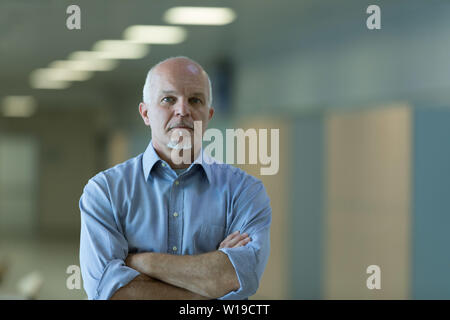 Half body portrait of senior businessman with folded arms and thoughtful expression. Stock Photo