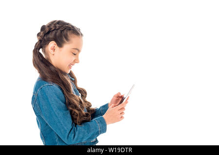 side view of smiling kid in denim jacket using smartphone isolated on white Stock Photo