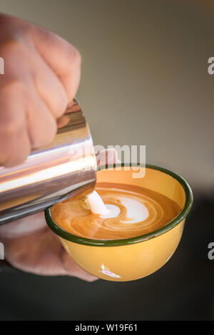 Hands of barista making cappuccino coffee pouring milk on espresso. Stock Photo