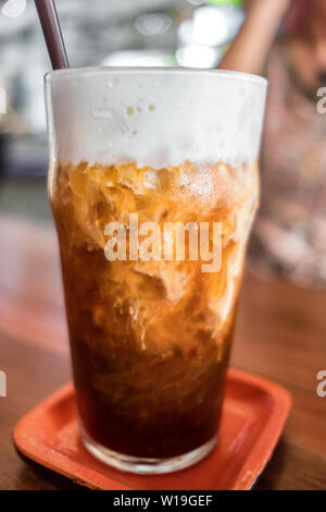 Ice coffee close-up on a wood table with cream being poured into it Stock Photo