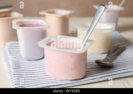 Composition with plastic cups with yogurt on white table Stock Photo