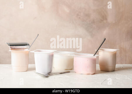 Composition with plastic cups with yogurt on white table Stock Photo