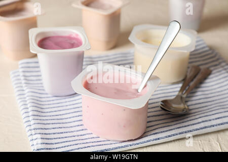 Composition with plastic cups with yogurt on white table Stock Photo