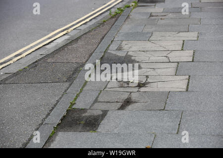 Pot holes and damaged concrete slabs on a path in Chichester, West Sussex, UK. Stock Photo
