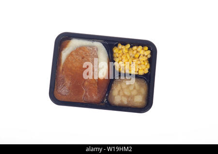 Still frozen Banquet uncooked tv dinner with meatloaf, mashed potatoes, gravy, sweet corn and apple dessert on white from above Stock Photo