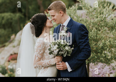 Bride and groom embracing on their wedding day. Just married couple in love sharing tender moments outside in nature. Stock Photo