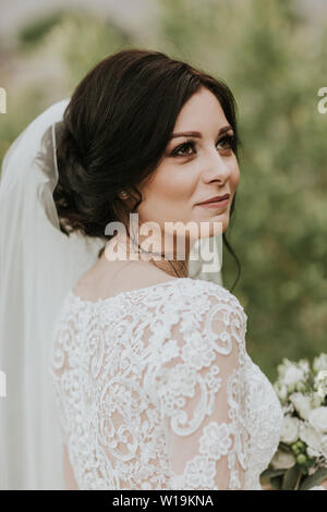 Bride on her wedding day. Portrait of young smiling bride wearing elegant lacey wedding gown and veil. Stock Photo