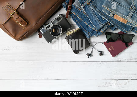 Accessories for travel plan, trip vacation, tourism - vintage leather bag and old jeans on wood background. Flat lay and copy space Stock Photo