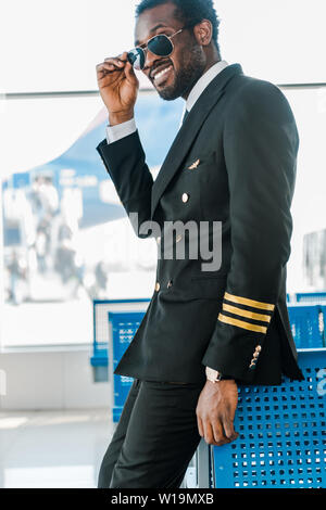 stylish smiling african american pilot in sunglasses in airport Stock Photo