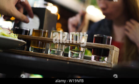 Multicolored transparent cocktails, a set of shots in one row, six servings on a wooden stand, substrate. Drink for the menu restaurant, bar, cafe Stock Photo