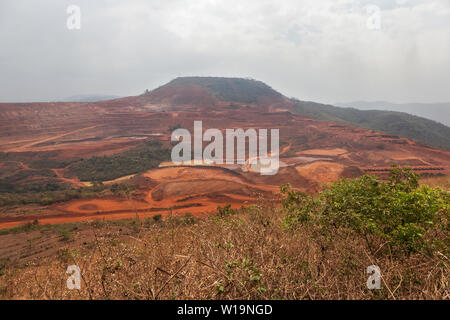 Mining operations for transporting and managing iron ore. Overall view of mine area before blast to left - with haul trucks parked right for safety. Stock Photo