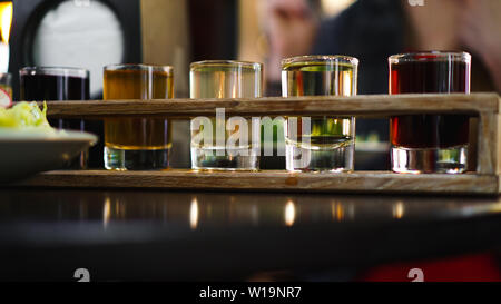 Multicolored transparent cocktails, a set of shots in one row, six servings on a wooden stand, substrate. Drink for the menu restaurant, bar, cafe Stock Photo