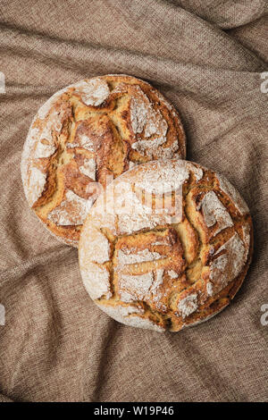 Brown Bread Rustic Linen Background Top Down View. Two Baked Whole Rye Grain Homemade Circle Loaf on Sackcloth Textile. Artisan Bakery Food Fresh Roun Stock Photo