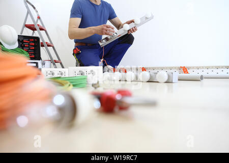 electrician at work with tools, puts the bulbs on a lamp at home, electric circuits, electrical wiring Stock Photo