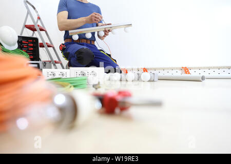 electrician works with the screwdriver installs the lamps, house electric circuits, electrical wiring Stock Photo