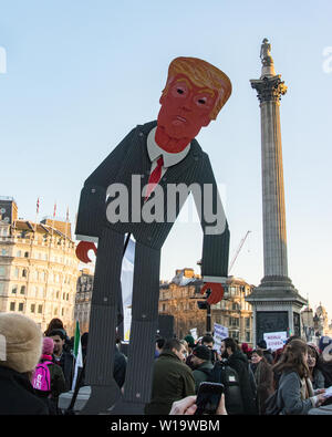 Women's March, London, UK, 21st January 2017. A giant cardboard puppet of Donald Trump is hoisted aloft in Trafalgar Square as women, men and children take to the streets in London to protest the day after the inauguration of President Donald Trump. Up to 10,000 took part in London as women worldwide marked the day by marching in an act of international solidarity. Many carried placards referencing statements made by Donald Trump, considered by many as anti-women or otherwise offensive. Stock Photo