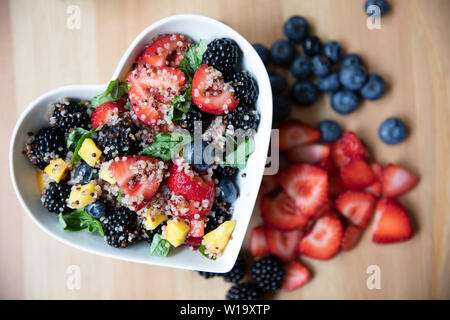 Healthy quinoa fruit salad in heart shaped bowl, flat lay. Stock Photo