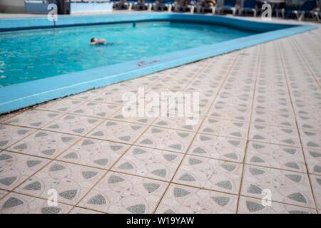 Tiled poolside and swimmer in the background Stock Photo