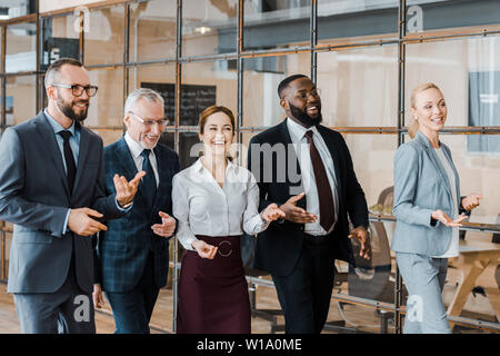 multicultural group of cheerful businessmen and happy businesswomen walking in office Stock Photo