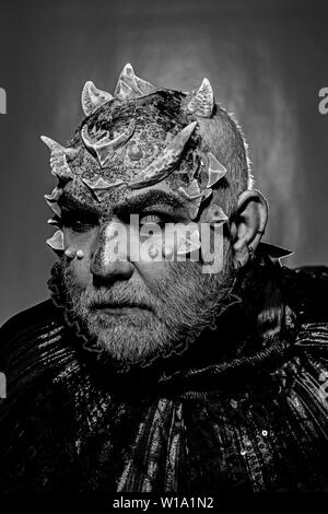 Demon with golden collar on black background. Man with thorns or warts, face covered with glitters. Fantasy concept. Alien, demon, sorcerer makeup Stock Photo