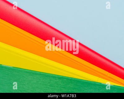 Colorful  stacked notebooks  on light blue background. Diagonal lines multicolored abstract background. Stock Photo