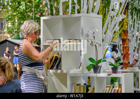 Zagreb, Croatia, July 1, 2019.  Lumen Station instalation in Park. Woman browsing through the books on offer in the reading pod shelf Stock Photo