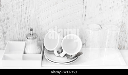 Coffee and tea making set of white cups, saucers, tea spoons and glasses on white porcelain tray. Hotel accomodation. Copy space. Stock Photo