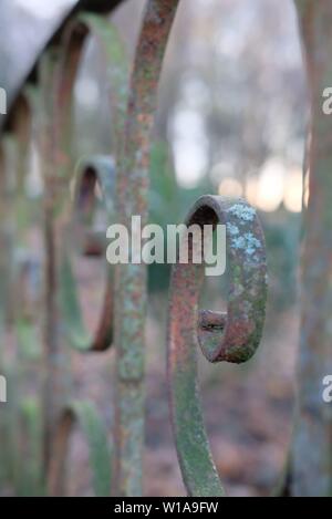 Closeup of metal rusty railing of a small old bridge with with spiral elements and some green moss on it. Stock Photo