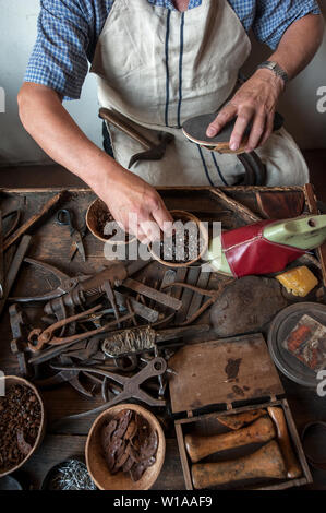 Shoemaker at work. Various tools and instrument are placed on the work bench. Stock Photo