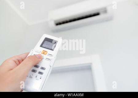 Adjusting temperature of air conditioner by remote. Air conditioning system Stock Photo