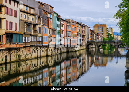 View of the Castres architecture on houses along the Agout river. Angled view from side of river with house reflection leading to old bridge