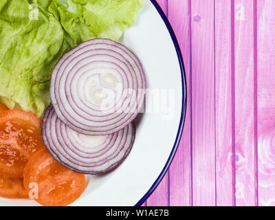 Fresh Garden Salad of Tomato Onion and Lettuce Against a Pink Background