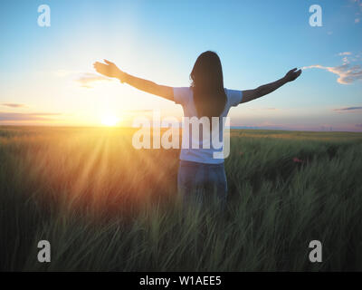 Woman feeling free in a beautiful natural setting, in what field at sunset Stock Photo