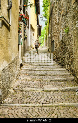 LAKE COMO, ITALY - JUNE 2019: Person walking up a narrrow lane with cobbled steps on the route of the Greenway del Lago di Como, which runs around par Stock Photo