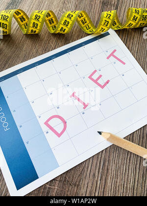 Diet plan concept. Measuring tape and diet plan on wooden background. Stock Photo