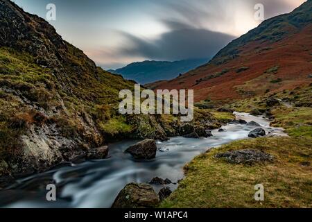 Brook run in autumnal hilly landscape with cloudy sky, Ambleside, Lake District National Park, Middle England, Great Britain Stock Photo