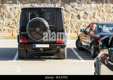 Varna, Bulgaria, February 10, 2019. Black car Mercedes-Benz G63 AMG on an outdoor parking lot on a sunny day, back view. Spare wheel on the jeep behin Stock Photo