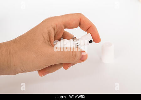 Female hand holding white medical aerosol can close-up. Drug in the form of a spray. Stock Photo