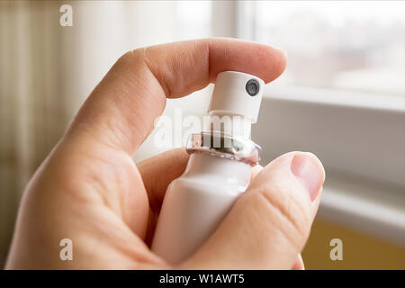 Female hand holding white medical aerosol can close up. Drug in the form of a spray. Stock Photo
