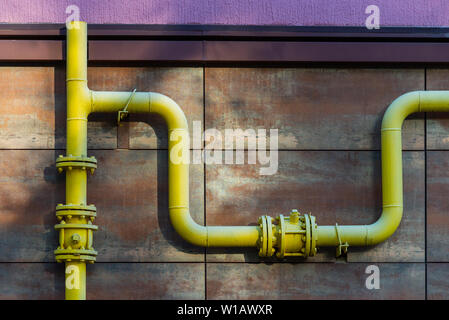 Yellow gas pipe in front of residential building wall. Stock Photo