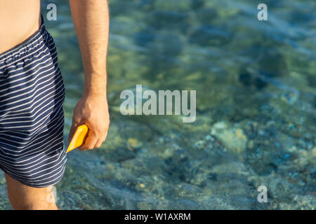 young man with wave-formed suncream on his shoulder standing at the beach, looking over the sea Stock Photo