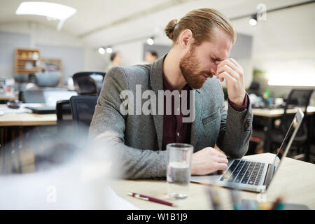 Side view portrait of exhausted businessman working in open space office Stock Photo