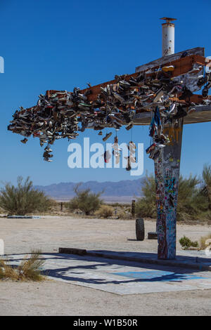 Old Shoes hanging on a demolished Gas Station on Highway 62, Rice, California, USA Stock Photo