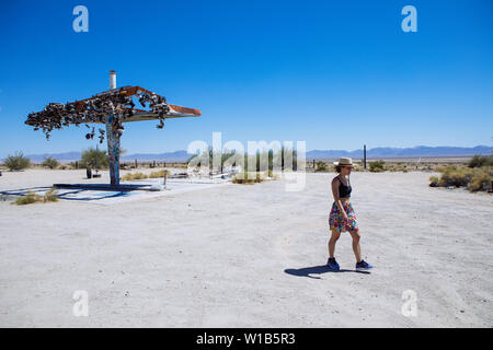 Woman walking away from Old Shoe Fence on demolished Gas Station on Highway 62, Rice, California, USA Stock Photo