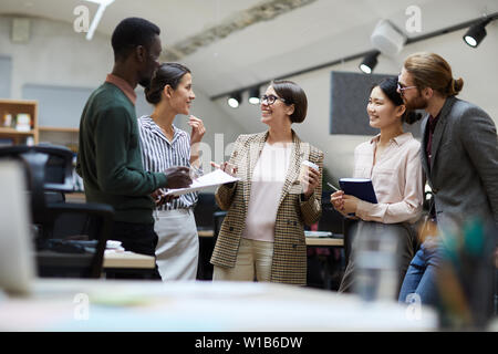 Multi-ethnic group of business people smiling cheerfully while chatting during coffee break in office, copy space Stock Photo