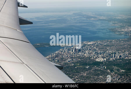 Aerial view of Toronto downtown highrise buildings and west edge of lake Ontario with curved airplane wing Canada Stock Photo