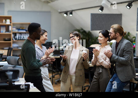 High angle view at multi-ethnic group of business people smiling cheerfully while chatting during coffee break in office, copy space Stock Photo